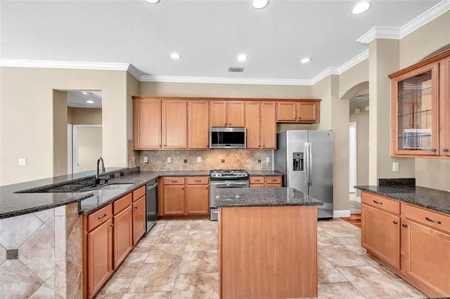 a large kitchen with stainless steel appliances granite countertop a stove a sink dishwasher a refrigerator and a microwave oven with granite countertops