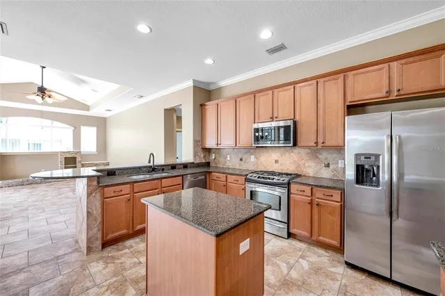 a kitchen with stainless steel appliances granite countertop a stove top oven a sink dishwasher a refrigerator and white cabinets with wooden floor