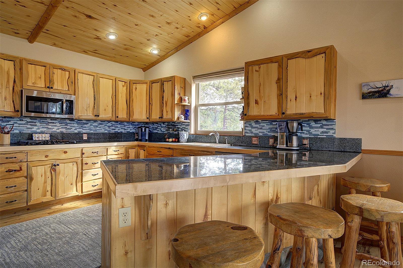 114 Star Lane Bailey, CO 80421 - Photo 17 of 41 a kitchen with granite countertop a sink and a wooden cabinets