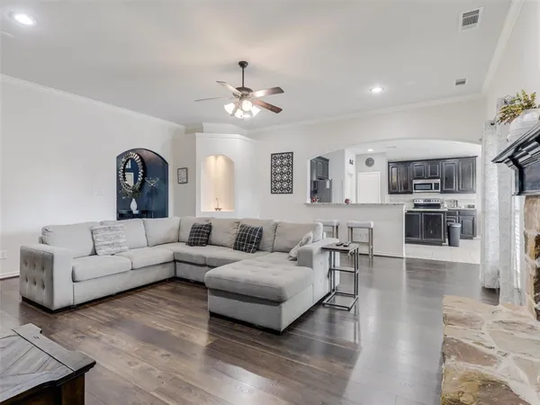 a living room with furniture kitchen view and a wooden floor