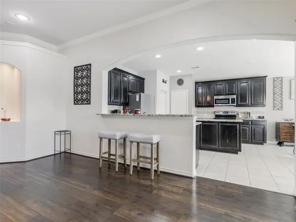 a kitchen with stainless steel appliances a microwave a stove a refrigerator a microwave a dining table and chairs
