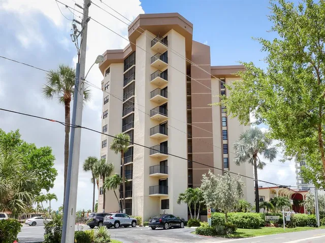 a front view of multi story residential apartment building with yard and retail shops