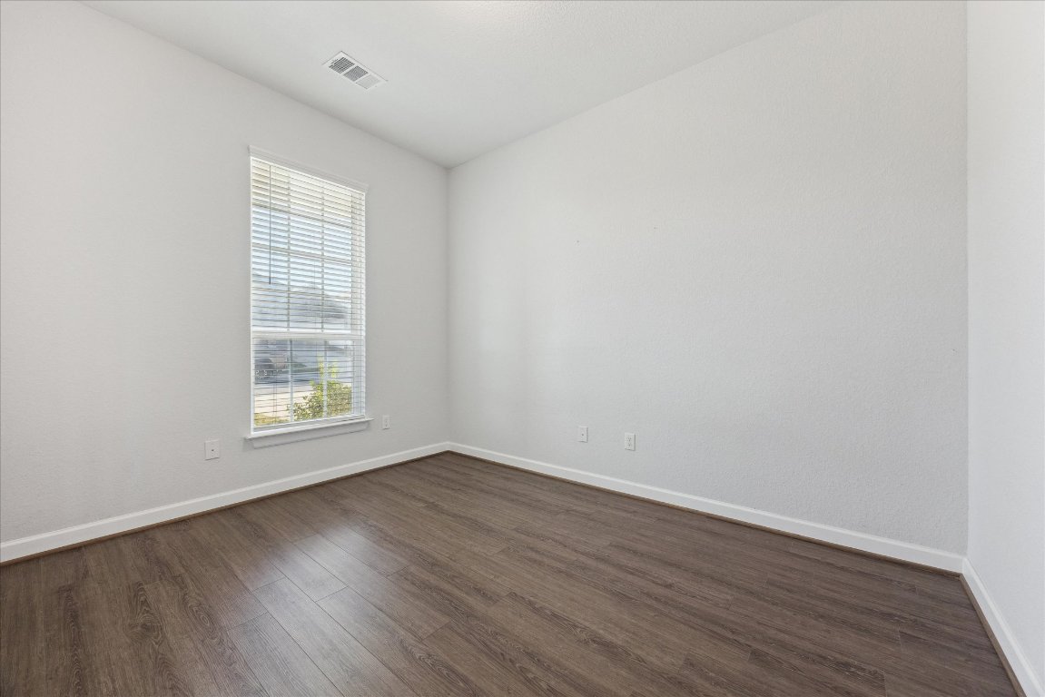 623 Baretta Loop Buda, TX 78610 - Photo 7 of 10 an empty room with wooden floor and windows