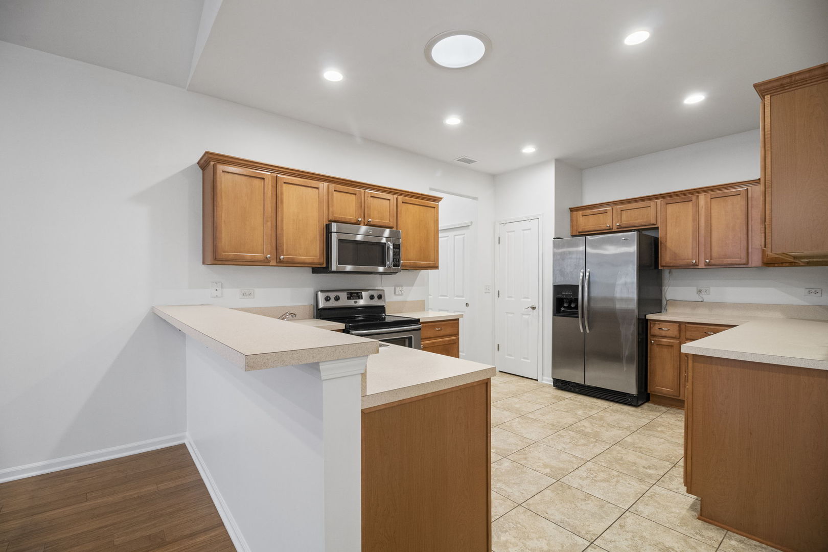 23908 Dayfield Drive, Unit 23908 Plainfield, IL 60586 - Photo 11 of 23 a kitchen with stainless steel appliances a refrigerator a stove a microwave a sink and dishwasher with wooden floor