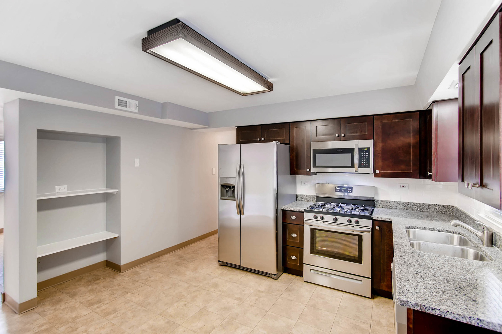 7233 38th Place Lyons, IL 60534 - Photo 4 of 26 a kitchen with stainless steel appliances kitchen island granite countertop a stove a refrigerator and a microwave