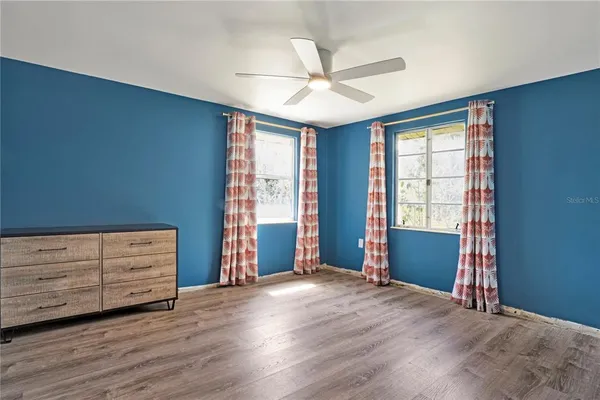 a view of an empty room with window and chandelier fan