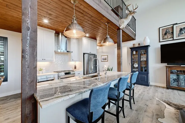 a kitchen with stainless steel appliances granite countertop a table chairs sink and cabinets