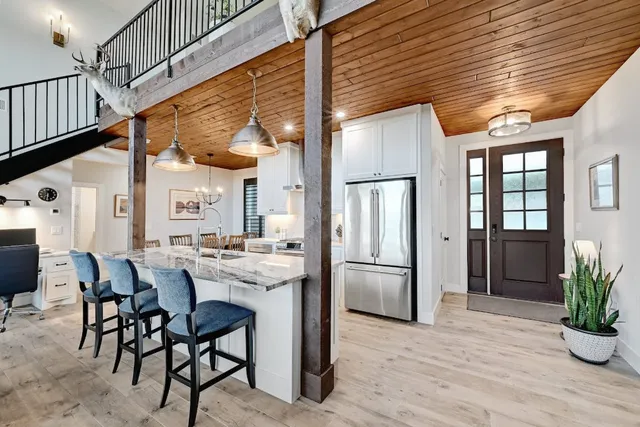 a kitchen with stainless steel appliances kitchen island granite countertop dining table chairs and cabinets
