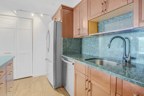 a kitchen with stainless steel appliances granite countertop a sink and a refrigerator