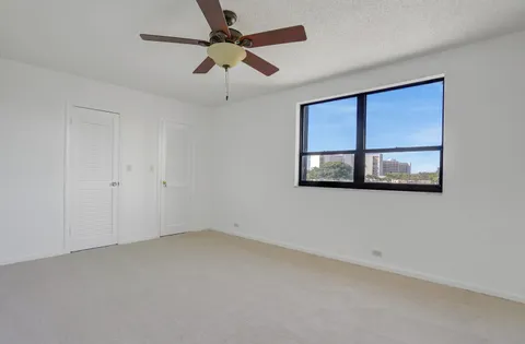 an empty room with wooden floor ceiling fan and windows