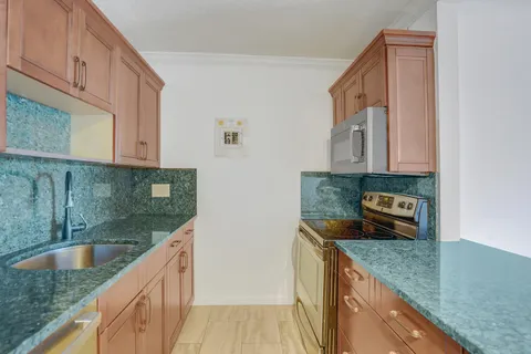 a kitchen with kitchen island granite countertop a sink a stove and cabinets