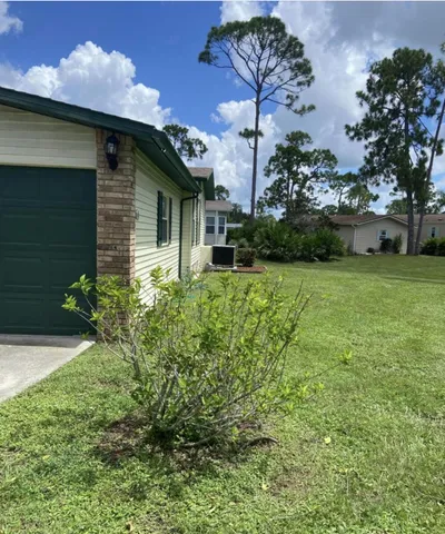 a backyard of a house with plants and large tree