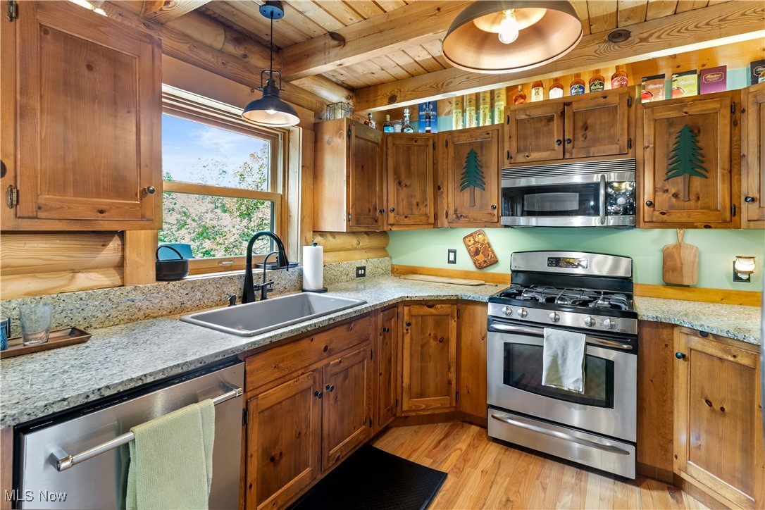 1784 North Medina Line Road Akron, OH 44333 - Photo 8 of 50 Kitchen featuring appliances with stainless steel finishes, a wooden ceiling with exposed beams, pendant lighting, light wood-style flooring, and brown cabinets