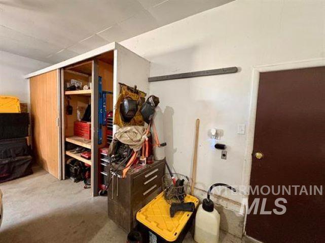 3197 Neeley Road American Falls, ID 83211 - Photo 12 of 45 Garage storage area featuring built-in cabinetry with sliding wood-finish doors, exposed shelving, and a concrete floor
