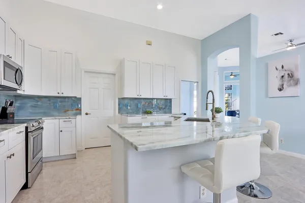 a kitchen with kitchen island granite countertop a sink cabinets and stainless steel appliances