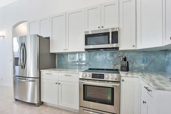 a kitchen with white cabinets and stainless steel appliances