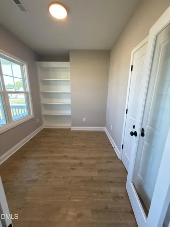 an empty room with wooden floor and windows