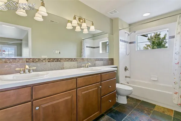 a spacious bathroom with a granite countertop toilet sink and mirror