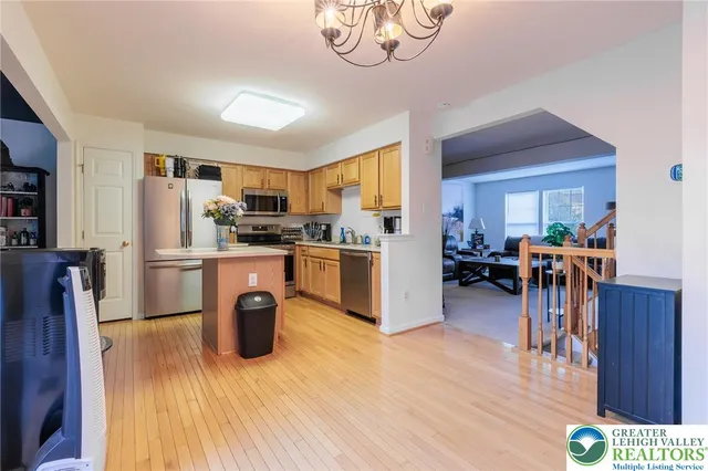 a open kitchen with stainless steel appliances granite countertop a refrigerator a stove top oven a dining table and chairs with wooden floor