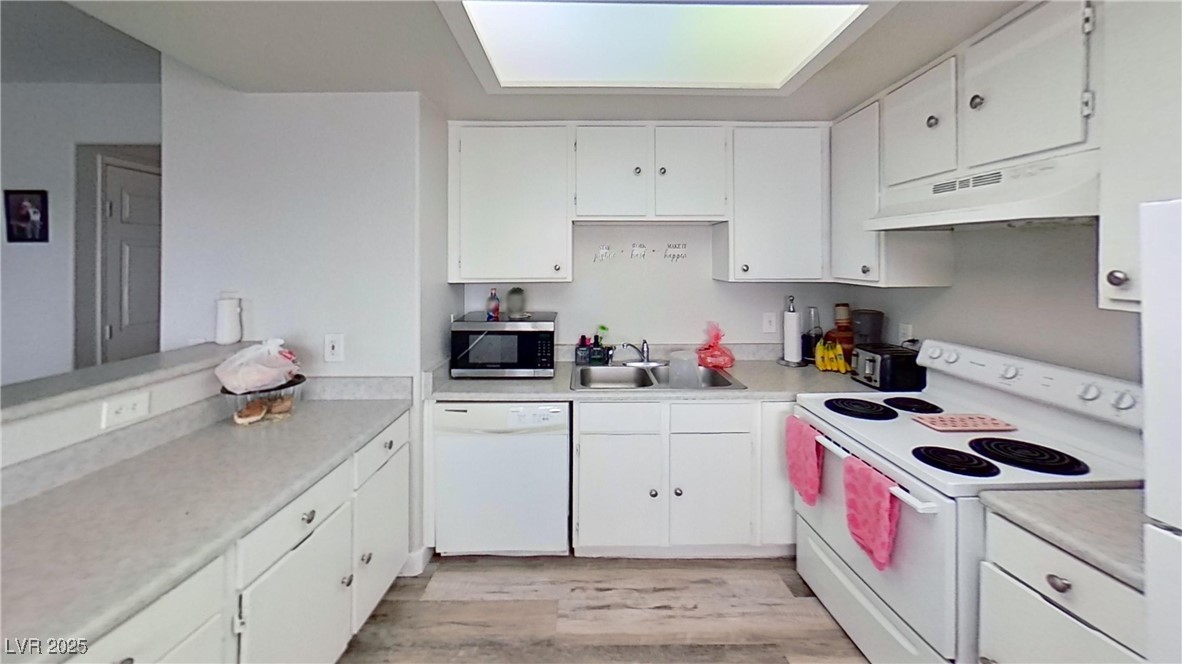 2201 James Bilbray Drive Las Vegas, NV 89108 - Photo 13 of 33 Kitchen featuring white appliances, light countertops, white cabinets, and light wood finished floors