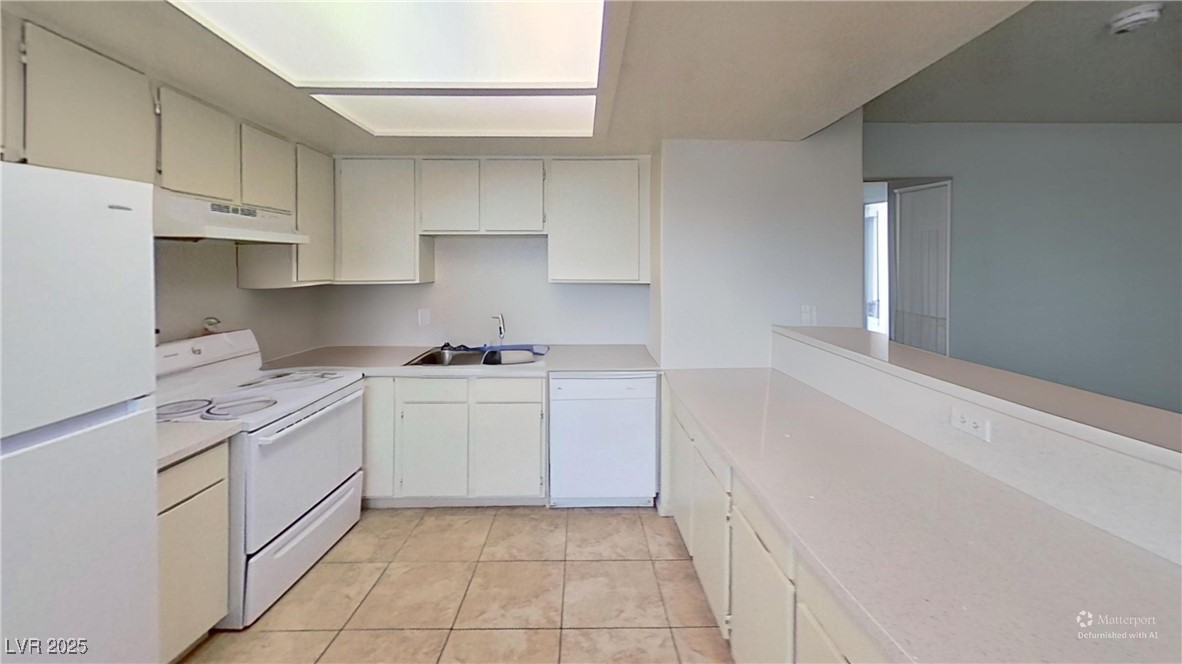 2201 James Bilbray Drive Las Vegas, NV 89108 - Photo 16 of 33 Kitchen featuring white appliances, light countertops, under cabinet range hood, light tile patterned floors, and white cabinetry