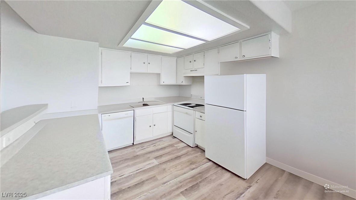 2201 James Bilbray Drive Las Vegas, NV 89108 - Photo 3 of 33 Kitchen featuring light countertops, white appliances, white cabinetry, light wood-style floors, and under cabinet range hood