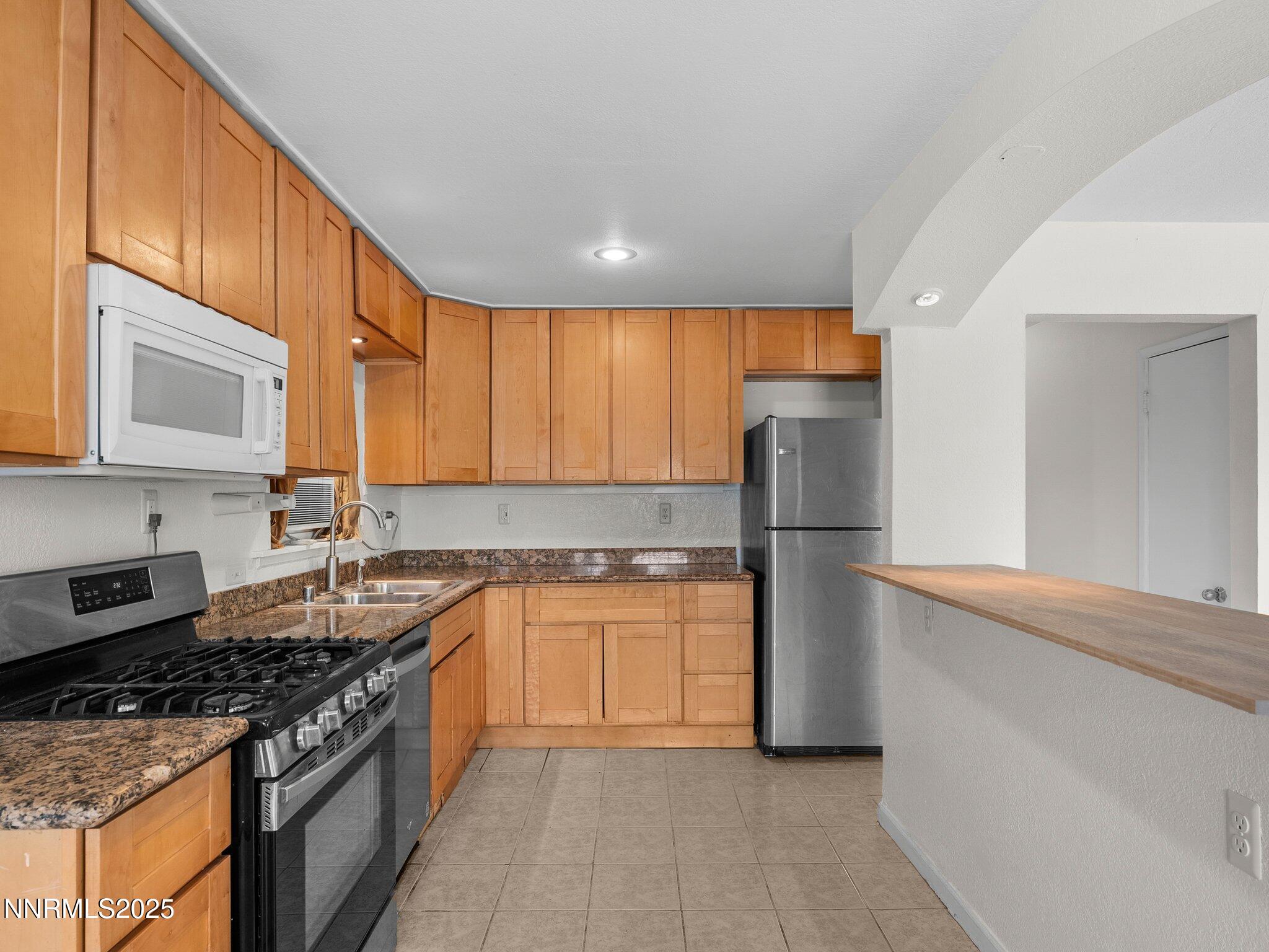 1955 Wilder Street Reno, NV 89512 - Photo 14 of 31 a kitchen with stainless steel appliances granite countertop a stove a refrigerator and a sink