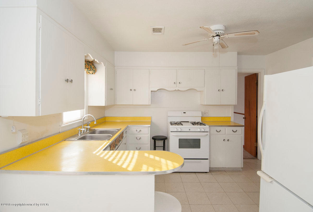 4315 South Travis Street Amarillo, TX 79110 - Photo 8 of 25 a kitchen with a white stove a sink dishwasher and a refrigerator with white countertops