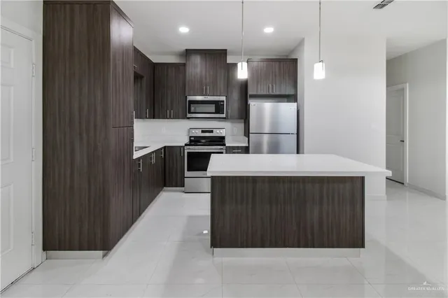 a kitchen with kitchen island stainless steel appliances a sink refrigerator and microwave