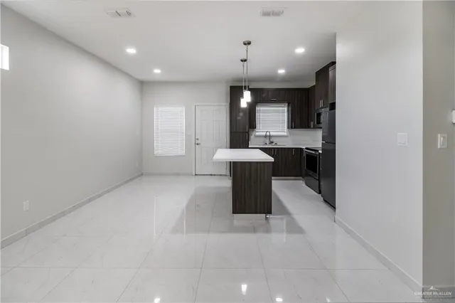 a view of a room with kitchen and chandelier fan