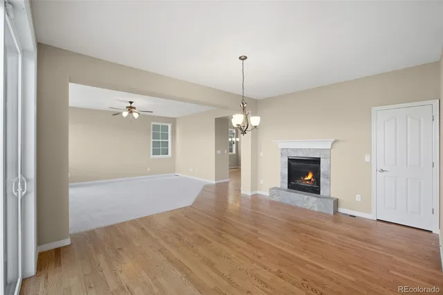 an empty room with wooden floor fireplace and staircase