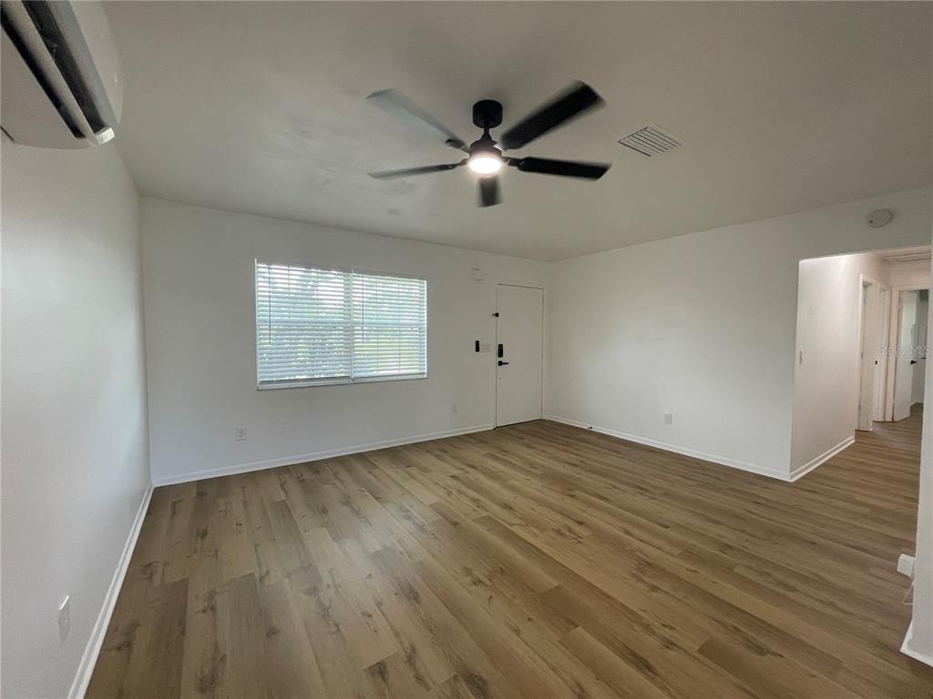 9244 Cyril Court Spring Hill, FL 34608 - Photo 13 of 30 an empty room with wooden floor fan and windows