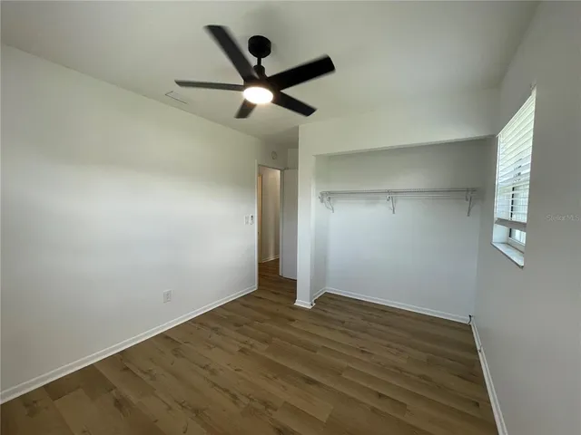 an empty room with wooden floor and ceiling fan
