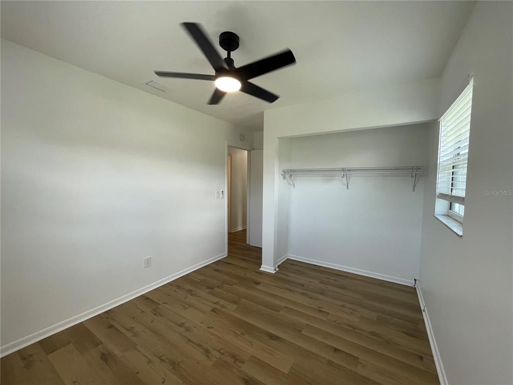 9244 Cyril Court Spring Hill, FL 34608 - Photo 14 of 30 an empty room with wooden floor and ceiling fan