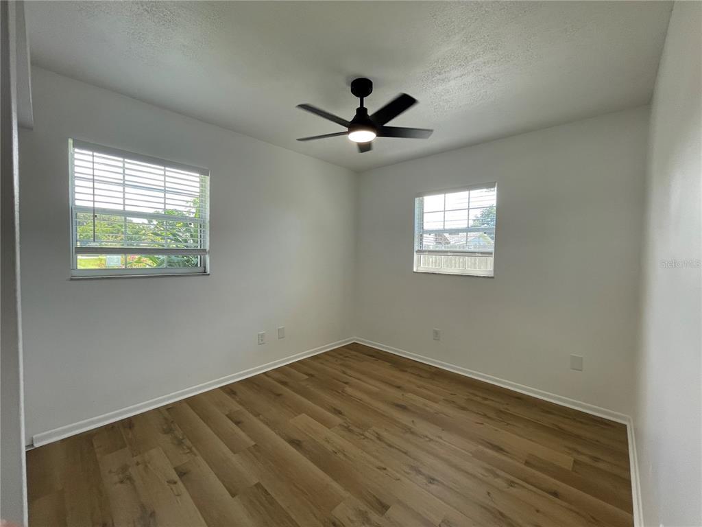 9244 Cyril Court Spring Hill, FL 34608 - Photo 15 of 30 an empty room with wooden floor ceiling fan and windows