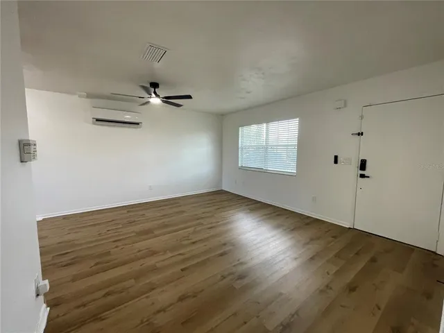 an empty room with wooden floor fan and windows
