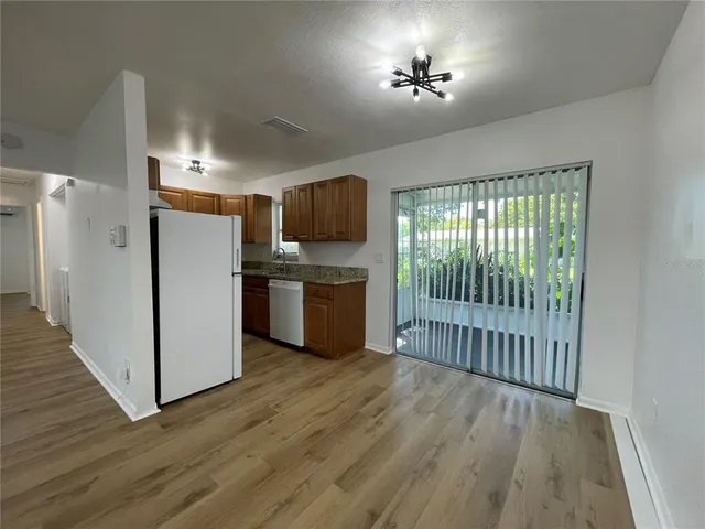 a view of a kitchen with a fridge wooden floor and a window
