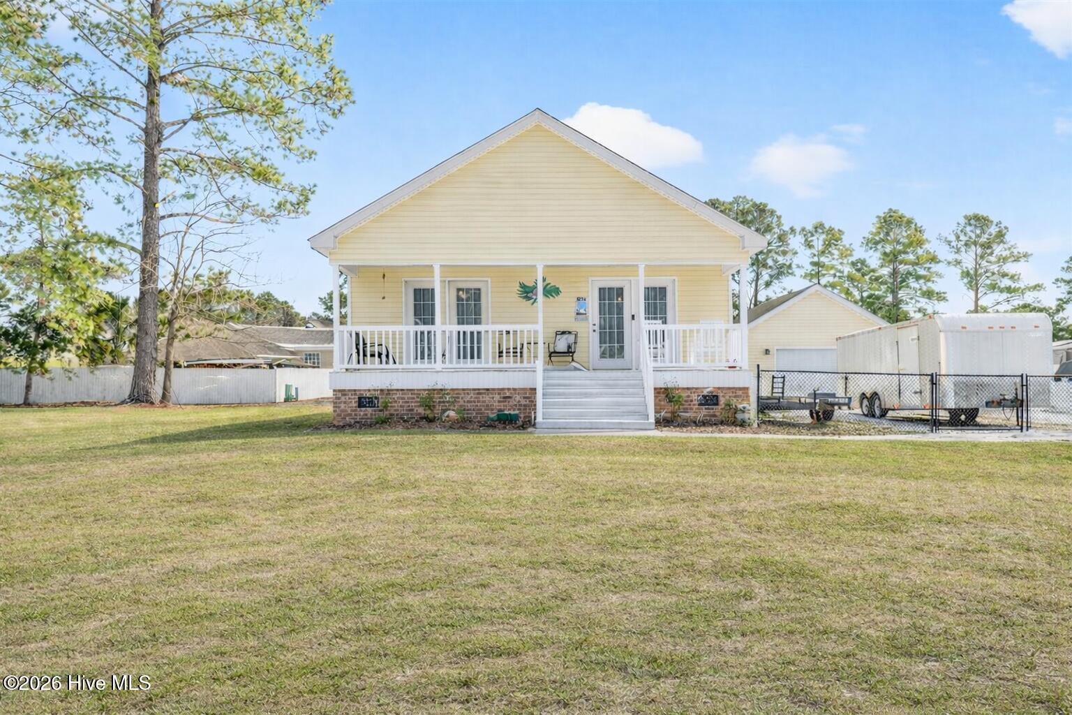 Charming coastal home at 1036 Palm Court in Carolina Shores featuring a welcoming covered front porch, manicured lawn, and classic curb appeal in the Village at Calabash.