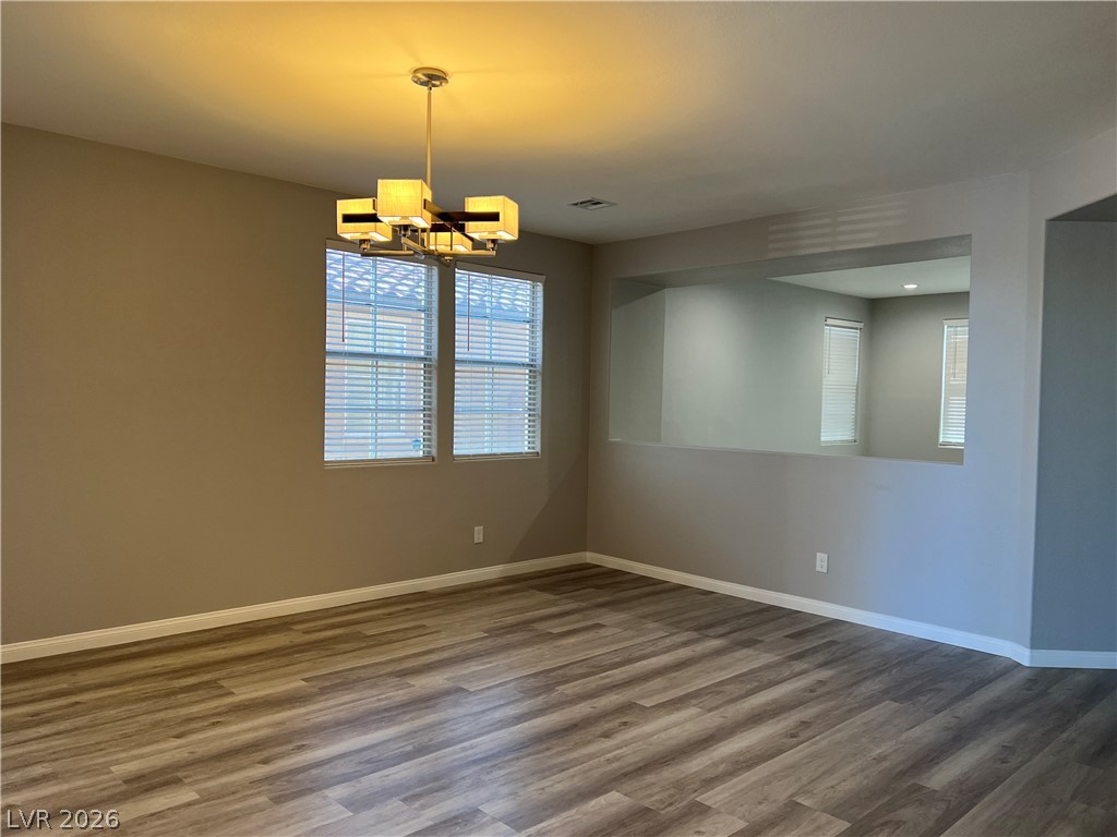 5981 Honeysuckle Ridge Street Las Vegas, NV 89148 - Photo 4 of 29 A contemporary chandelier illuminates the dining area, featuring attractive wood-look flooring and a unique pass-through window.