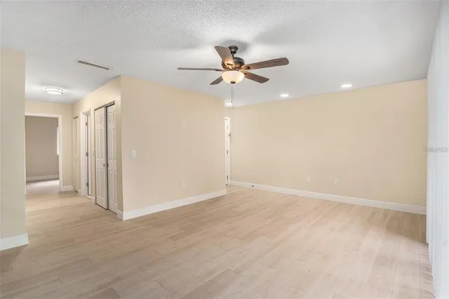 an empty room with wooden floor ceiling fan and window