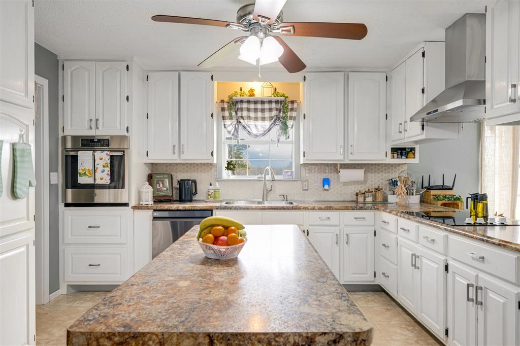 1876 Farm To Market 906 Powderly, TX 75473 - Photo 7 of 38 a kitchen with kitchen island granite countertop a stove a sink and a refrigerator
