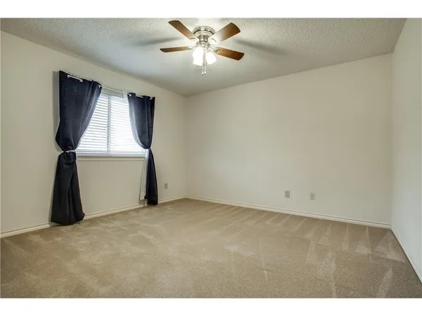 a view of an empty room and chandelier fan