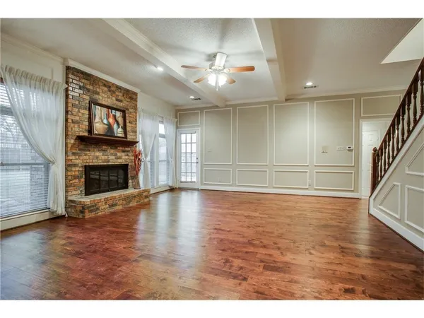 a view of an empty room with wooden floor fireplace and a window