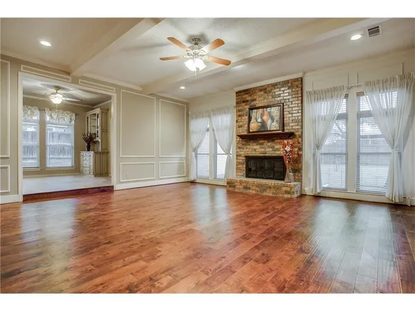 an empty room with wooden floor fireplace and windows