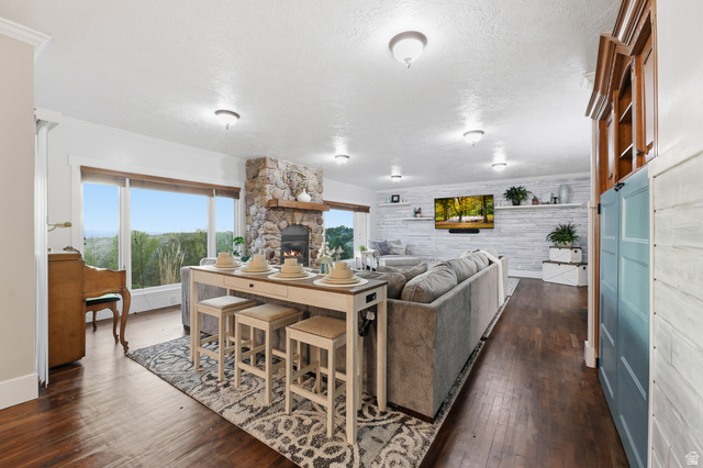 2342 Charros Road Sandy, UT 84092 - Photo 18 of 94 Expansive living area featuring large windows, a stone-clad fireplace with a wood mantle, and wood-finish flooring
