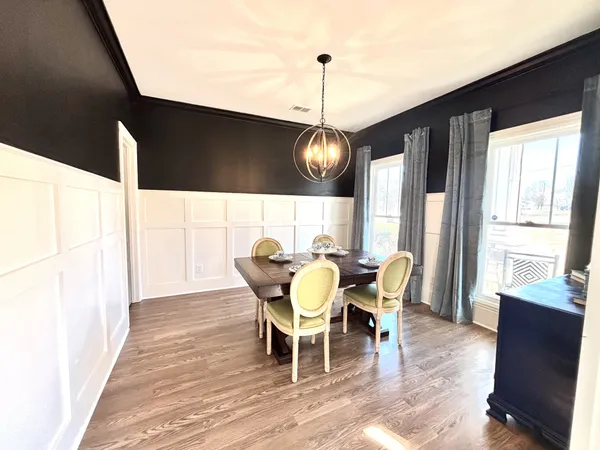 a dining room with wooden floor a chandelier a wooden table and chairs
