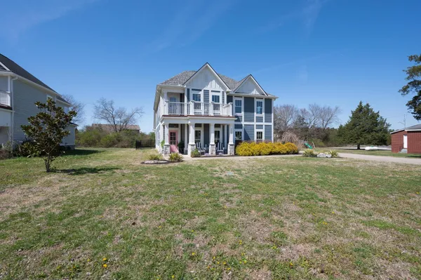 a view of a large house with a big yard and large trees
