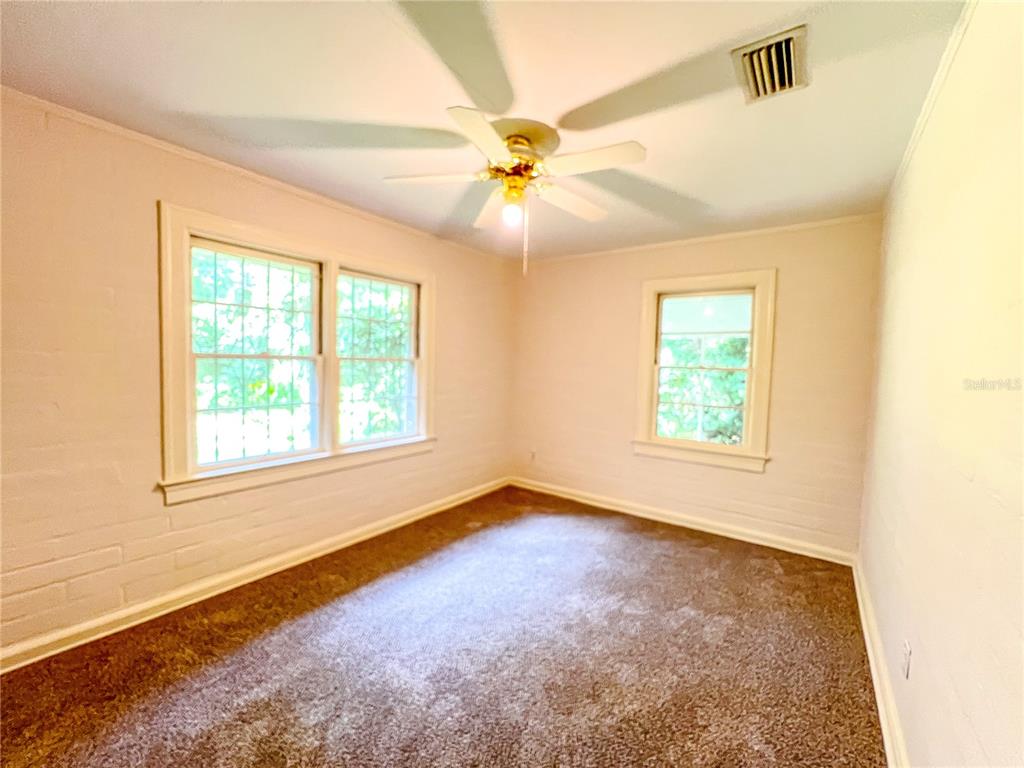 1403 Northwest 11th Road Gainesville, FL 32605 - Photo 11 of 15 an empty room with windows and ceiling fan