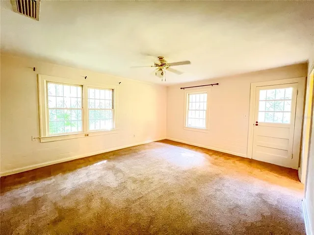 an empty room with windows and ceiling fan