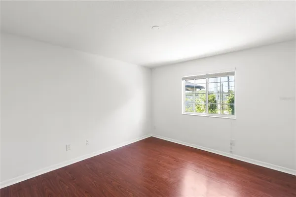 an empty room with wooden floor and window